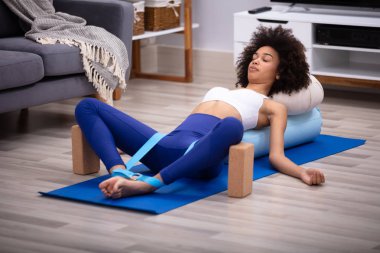 Genç kadın egzersiz Yoga kemer ve iki blok yaparak Fitness Mat yatarken rahat
