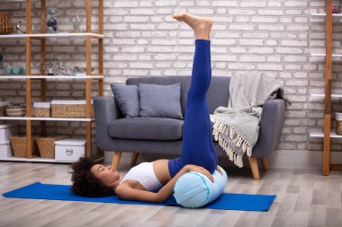 Genç bir kadının bacak egzersiz Yoga Mat oturma odasında yukarı yapması