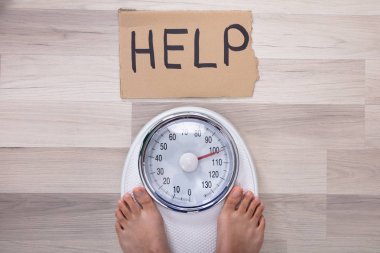 Yüksek yardım görünümünü karton ölçek ağırlığında üzerinde kadının ayakları üzerine işaret