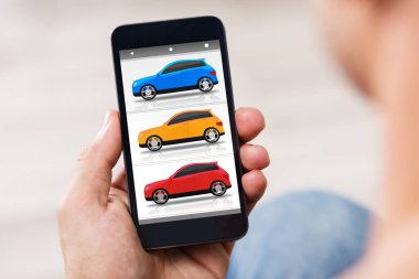 Ekranda renkli arabalar ile cep telefonu tutan bir kişinin el Close-Up