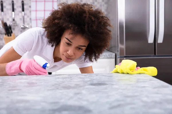 洗浄スプレー洗剤と黄色のナプキンで汚い台所カウンター幸せなアフリカ若い女 — ストック写真