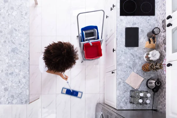 现代厨房里用拖把清洁白色地板的女管理员 — 图库照片