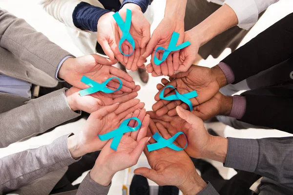 Group Of Businesspeople Holding Teal Ribbons To Support Ovarian Cancer Awareness
