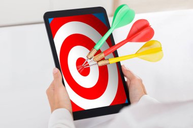 Renkli Dart hedef ile dijital Tablet üzerinde beyaz Resepsiyon tutan insan el