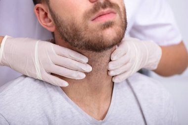 Doktor 'un Eli Eldiven Giyiyor. Tiroid bezinin elle muayene edilmesini sağlıyor.