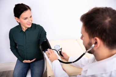 Genç erkek doktor kliniğinde bayan hasta gülümseyen, kan basıncı kontrol