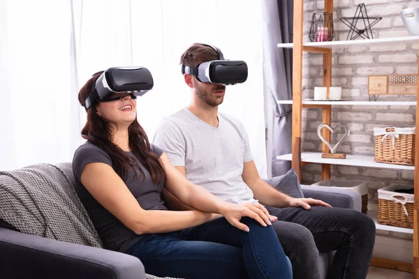 坐在沙发上体验虚拟现实耳机的年轻情侣 — 图库照片
