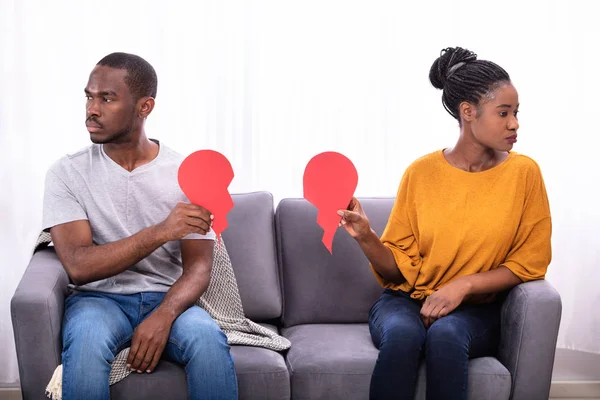 Casal Sentado Sofá Ignorando Uns Aos Outros Segurando Coração Vermelho — Fotografia de Stock