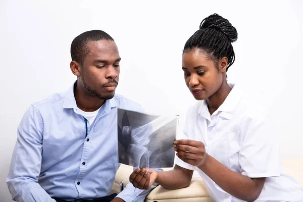 Doctora Joven Mostrando Radiografía Rodilla Paciente Masculino — Foto de Stock