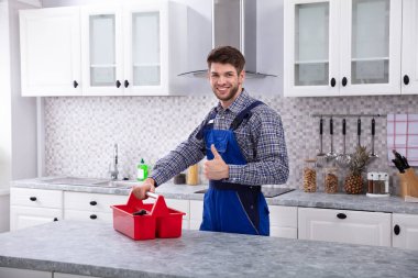 Mutlu erkek tamirci mutfakta başparmak el hareketi Toolbox ile