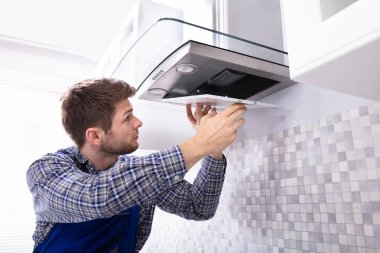 Mutfak odasında genç erkek sabitleme mutfak aspiratör filtre yan görünüm