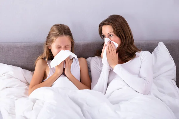 Mãe Filha Sofrendo Frio Soprando Seu Nariz Com Lenço Cama — Fotografia de Stock