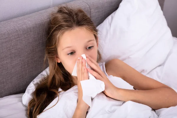 女孩遭受冷吹她的鼻子与手帕在床上 — 图库照片