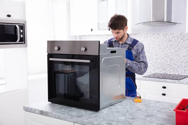 Jovem Reparador Masculino Reparando Forno Usando Multímetro Digital Cozinha — Fotografia de Stock
