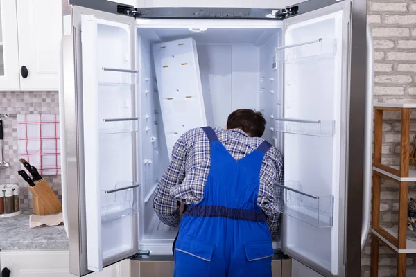 若いサービスマンは デジタルマルチメーターで冷蔵庫をチェック — ストック写真