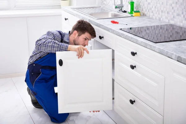 Hockende Reparaturfirma Repariert Die Tür Der Küchenspüle — Stockfoto