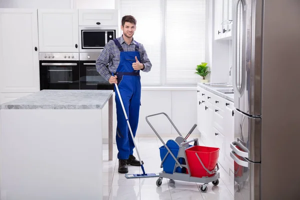 男性看门人清洁地板与拖把在厨房 — 图库照片