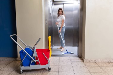Mutlu kadın kapıcı Asansör paspas ile Temizleme