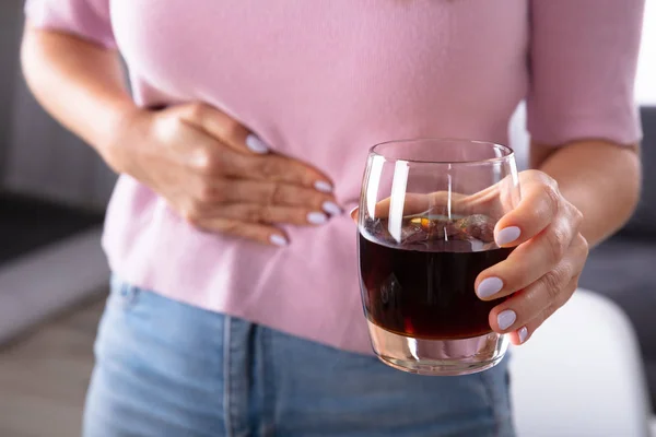 Midsection View Of A Woman Suffering From Stomach Pain Holding Glass Of Drink