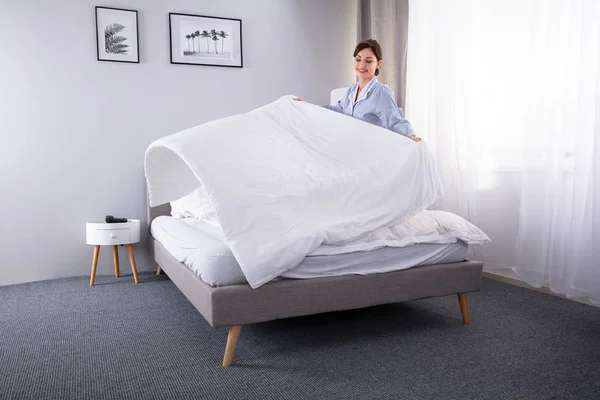 Smiling Young Female Housekeeper Arranging Bedsheet Bed Hotel Room — Stock Photo, Image