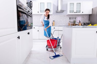 Mutlu kadın hademe mutfak paspas ile zemin temizleme