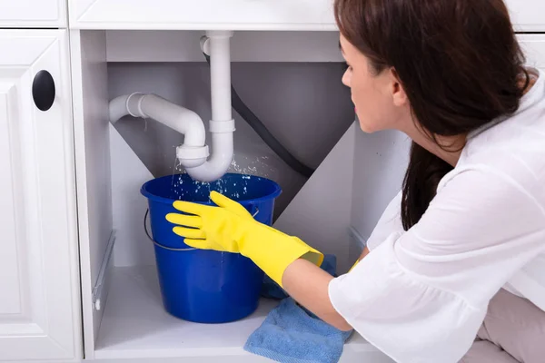 Close Young Woman Placing Blue Bucket Water Leaking Sink Pipe — Stock Photo, Image