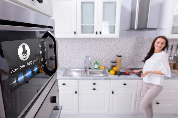 一个具有语音识别功能的烤箱近女站在后台的特写镜头 — 图库照片