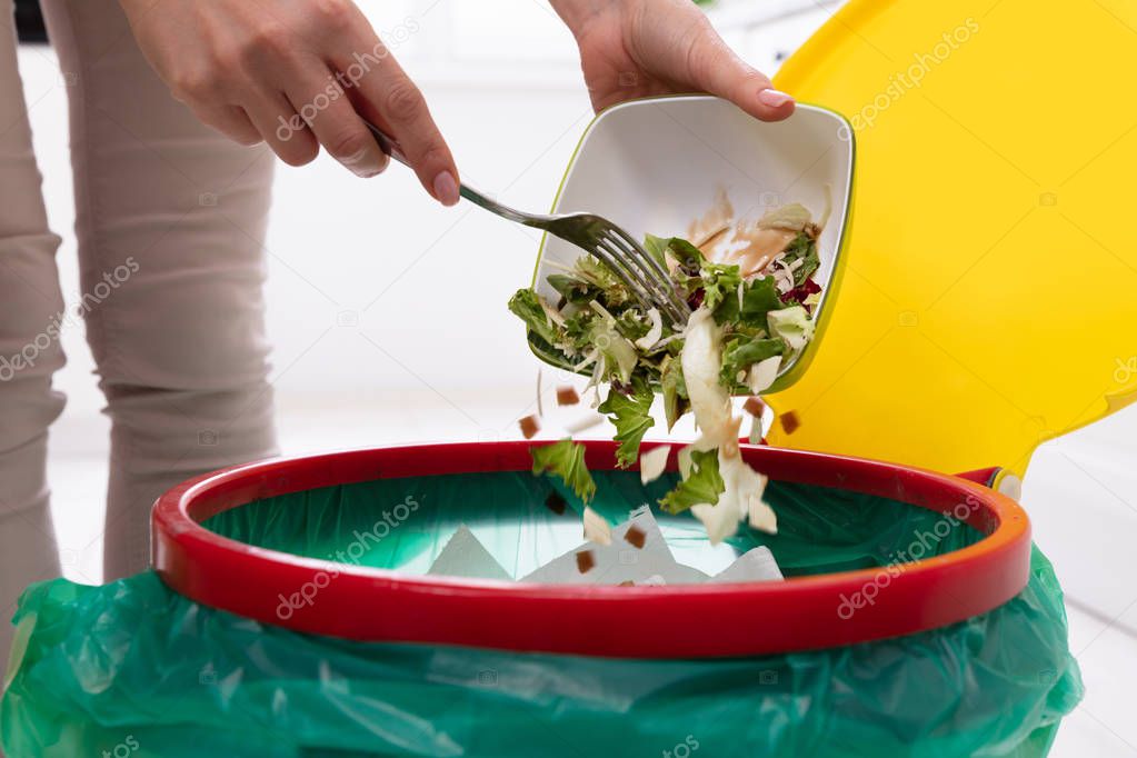 Close-up Of A Woman's Hand Throwing Vegetables In Trash Bin
