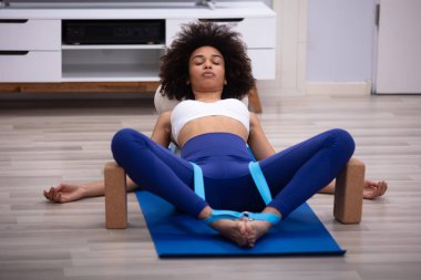 Genç kadın egzersiz Yoga kemer ve iki blok yaparak Fitness Mat yatarken rahat
