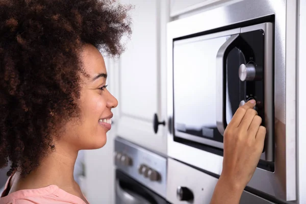 Närbild Leende Ung Kvinna Justera Temperaturen Mikrovågsugn — Stockfoto