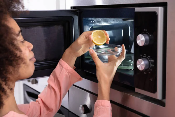 Woman Hand Squeezing Halved Lemon Glass Bowl Open Microwave Oven — Stock Photo, Image