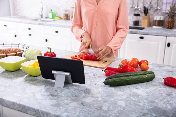 Mutfakta Kırmızı Çan Biberini Keserken Kadın Dijital Tablet Kullanıyor — Stok fotoğraf