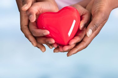 Anne ve çocuk eller mavi arka plan üzerinde kırmızı kalp tutan