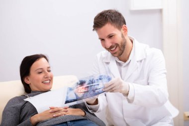 Bir erkek doktorun klinikteki kadın hastaya röntgen çekmesini açıklarken yakın plan.