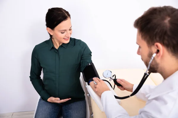 Joven Médico Masculino Revisando Presión Arterial Sonriente Paciente Femenina Clínica —  Fotos de Stock