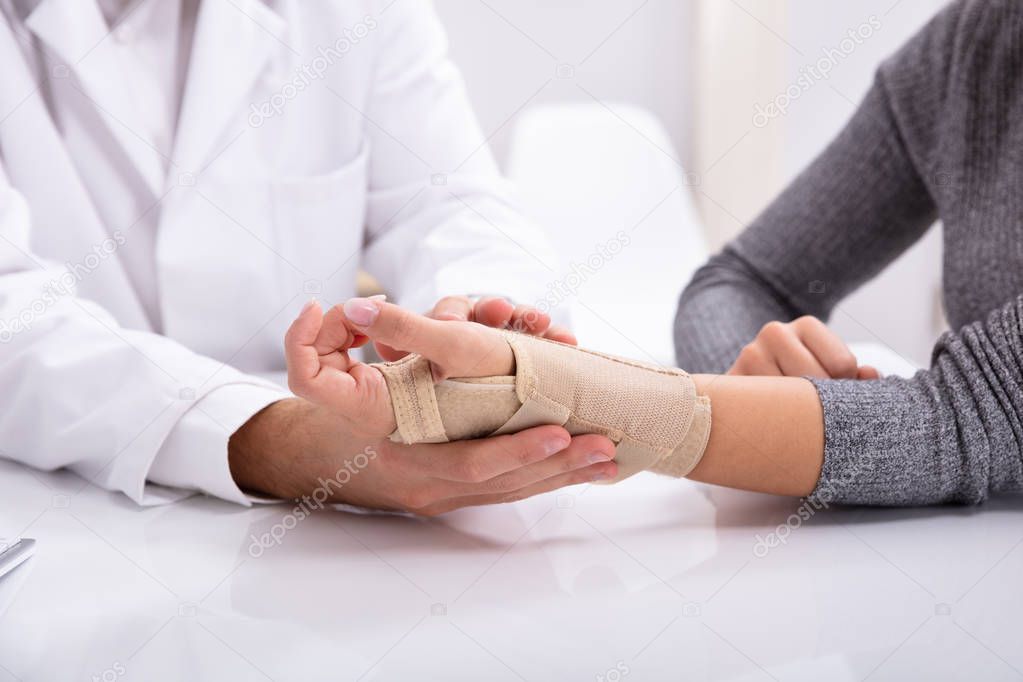 Close-up Of Doctor's Hand Checking Fractured Hand Of A Woman