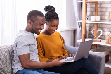 Dizüstü bilgisayar kullanarak koltukta oturan mutlu genç Çift