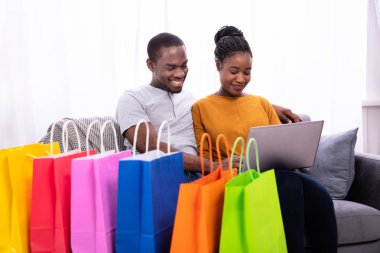 Genç çift laptop renkli alışveriş torbaları yakınındaki alışveriş gülümseyen