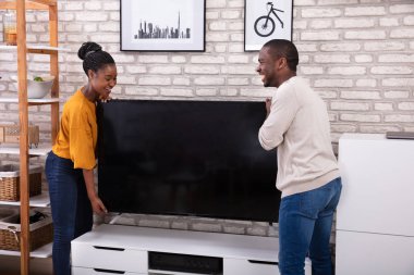 Evde televizyon kaldırma genç Afrikalı çift yan görünüm