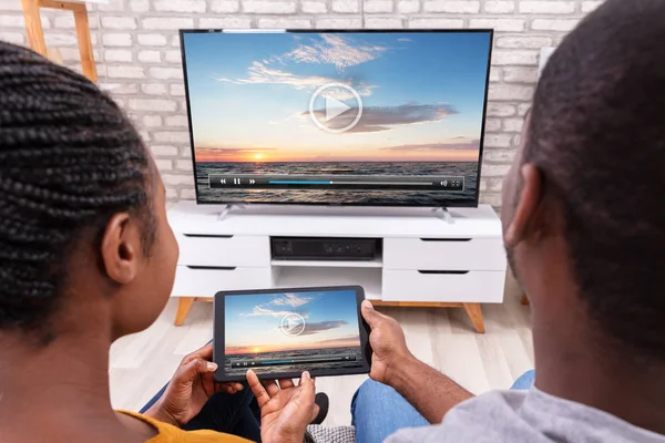 Afrykańska Para Siedzi Kanapie Łączącej Kanał Telewizyjny Przez Bezprzewodowy Tablecie — Zdjęcie stockowe