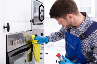 Mutfakta fırın temizleyen hizmetlinin yakın çekimi.