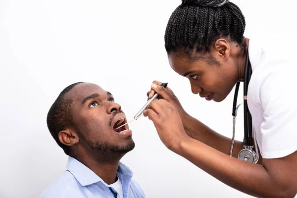 白种人背景下 女医生用舌音抑制剂检查男人的鼻涕 — 图库照片