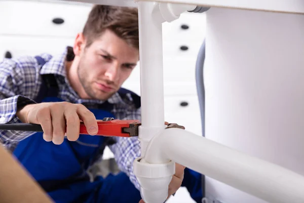 Junger Männlicher Klempner Repariert Spülrohr Mit Einstellbarem Schraubenschlüssel — Stockfoto