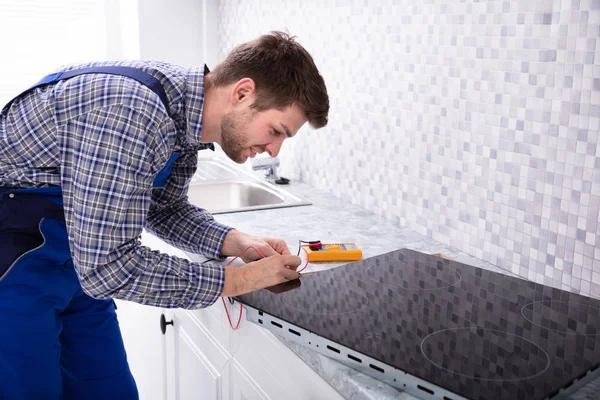 Seitenansicht Eines Jungen Reparateurs Der Einen Induktionsherd Mit Digitalem Multimeter — Stockfoto