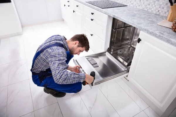 Junger Reparateur Repariert Geschirrspüler Mit Elektrobohrmaschine Küche — Stockfoto