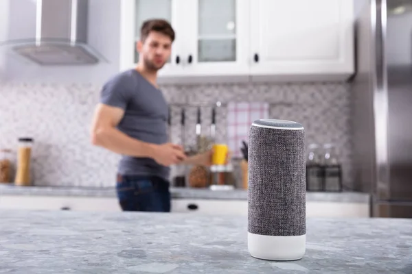 Close-up Of Wireless Speaker In Front Of Man Cutting Vegetables In Kitchen