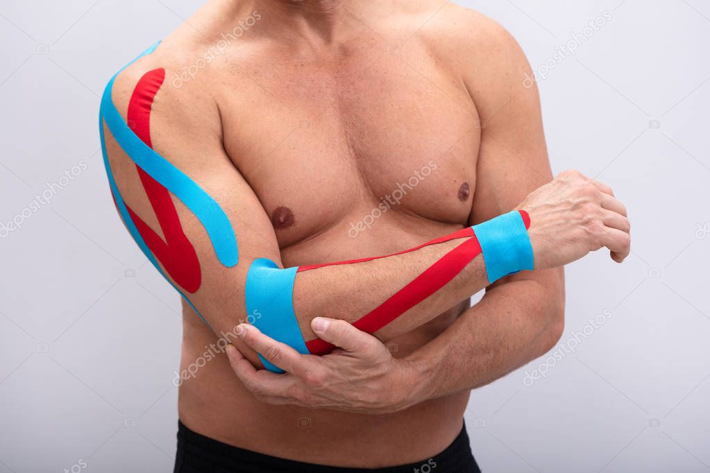 Mid-section  Man With Physio Tape On His Hand Against White Background. Body shape was altered during retouching