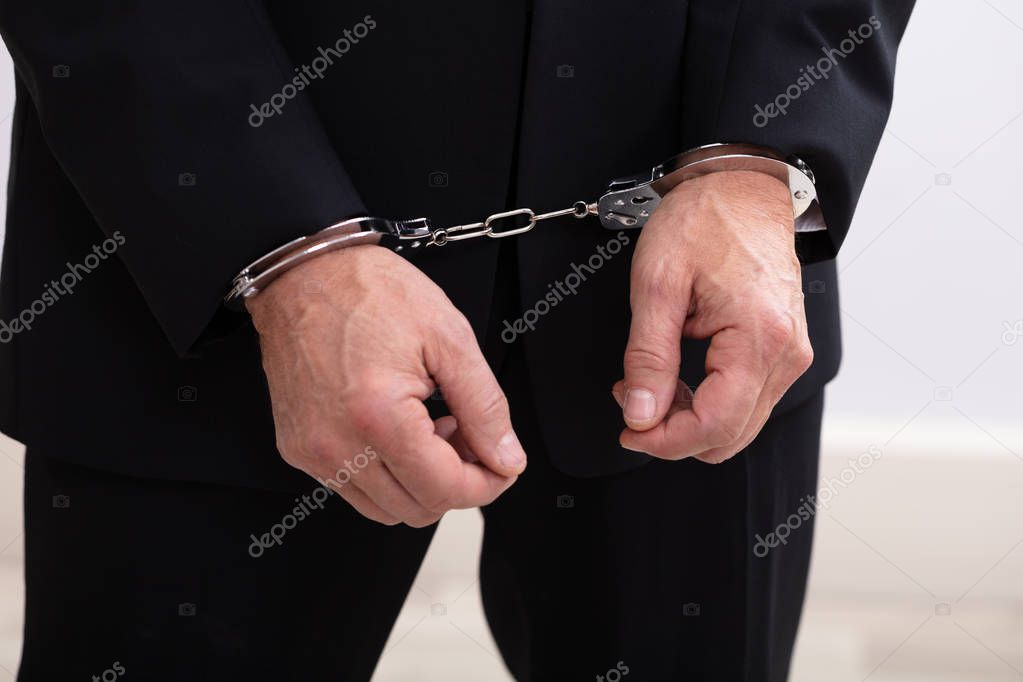 Photo of criminal businessman arrested wearing handcuffs