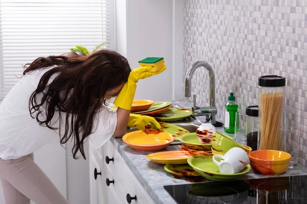 台所に汚れた食器をシンク近く傾いて疲れの若い女性の側面図 — ストック写真