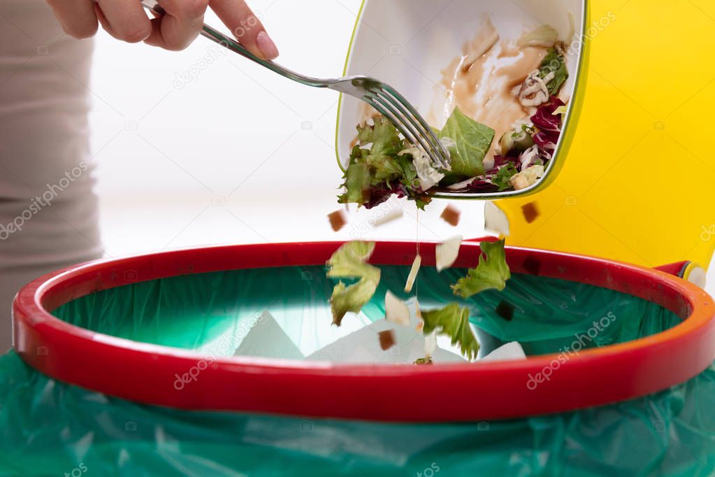 Close-up Of A Woman's Hand Throwing Vegetables In Trash Bin